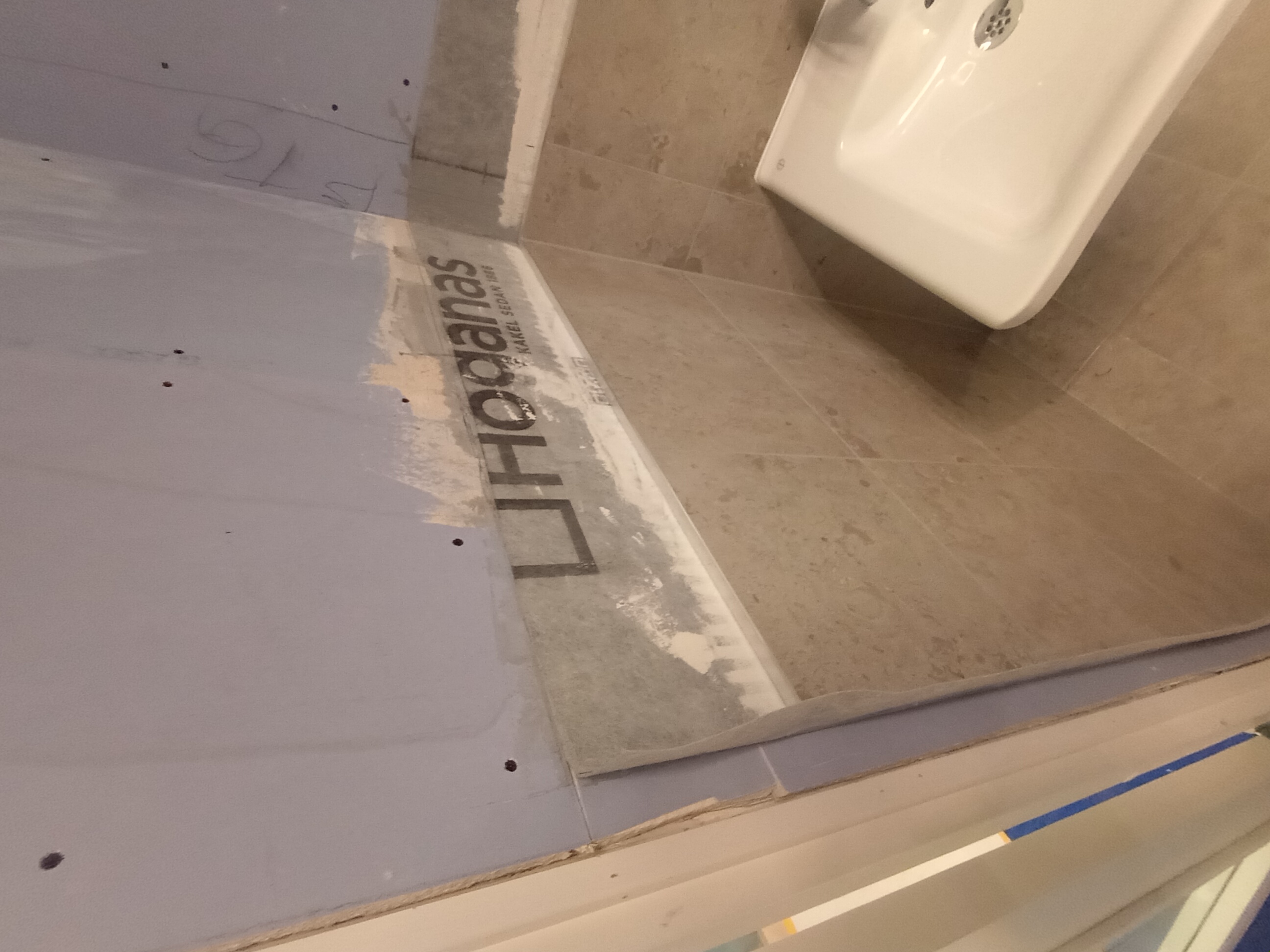 Detalj av väggyta och övergång mot kakel inför målning